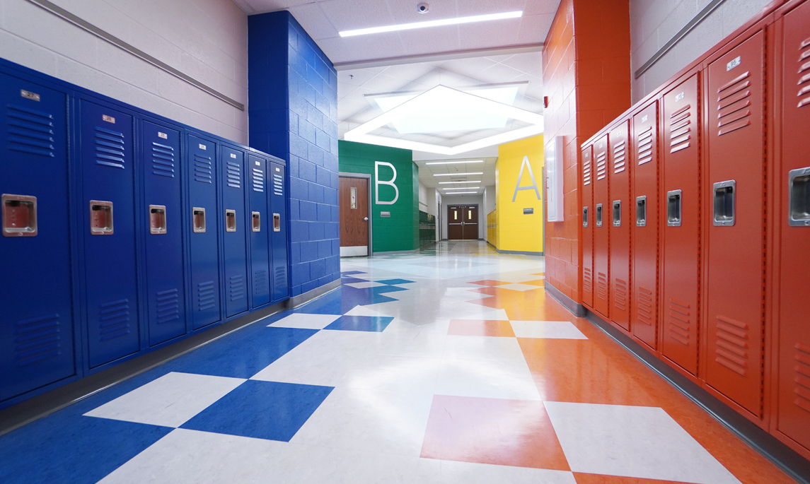 School hallway with multiple colors of vinyl flooring with colored lockers along wall